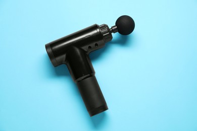 Photo of One black percussive massager on light blue background, top view