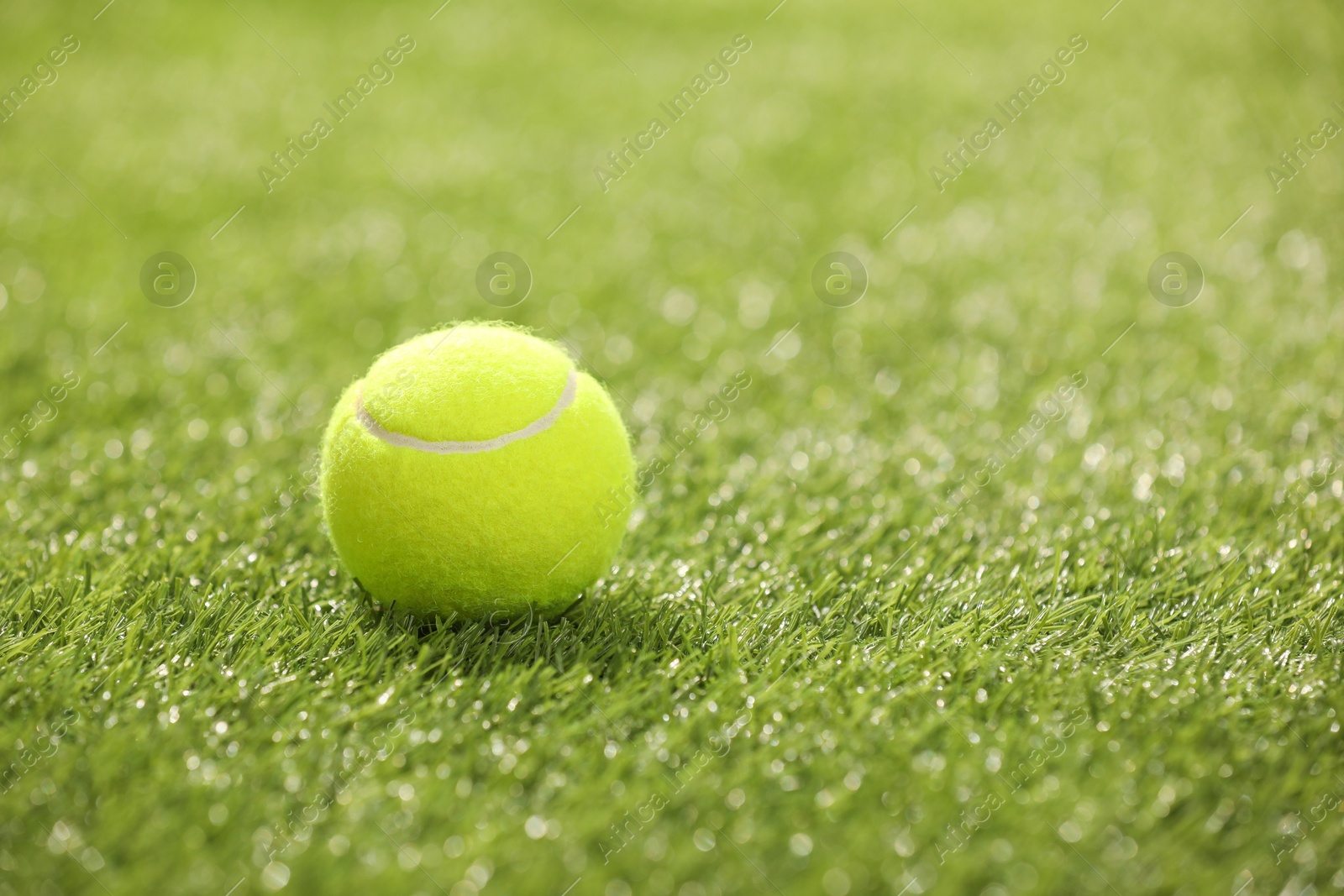 Photo of Tennis ball on green artificial grass, space for text