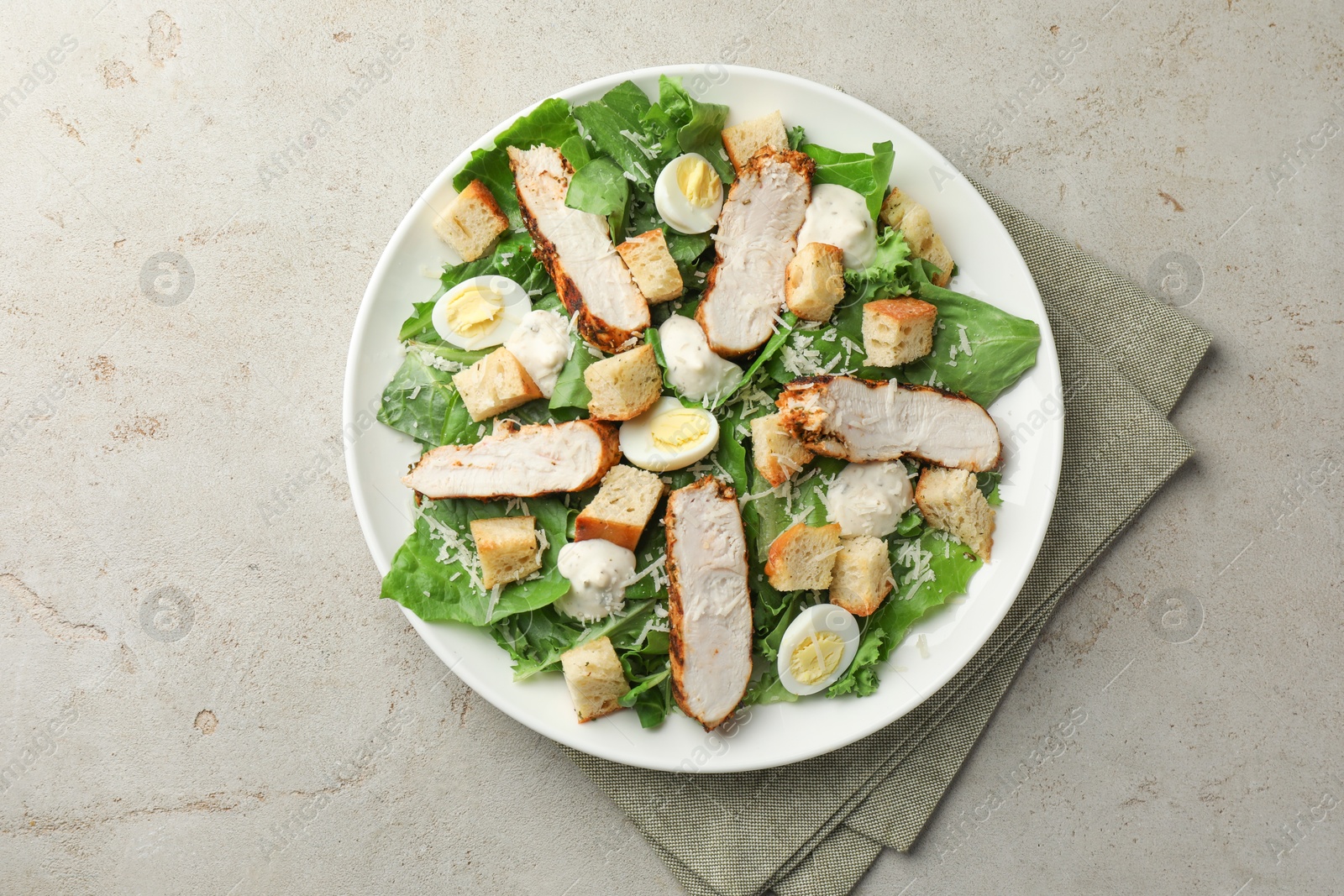 Photo of Tasty Caesar salad with chicken on light grey table, top view