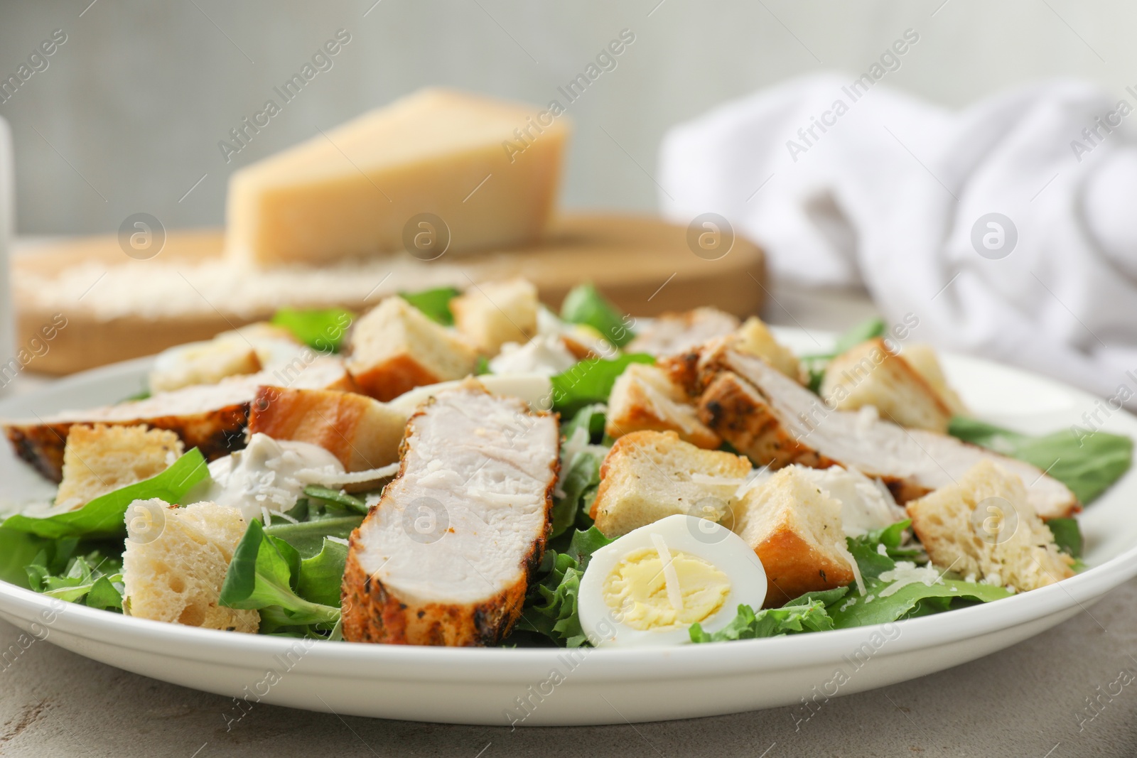 Photo of Tasty Caesar salad with chicken on light grey table, closeup