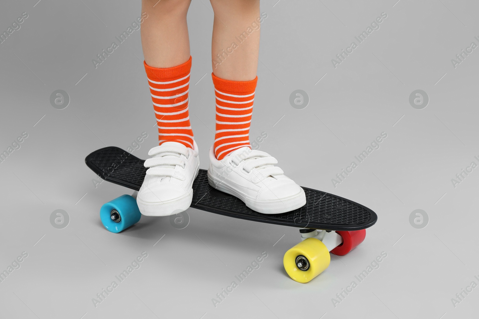 Photo of Little boy with skateboard on light grey background, closeup