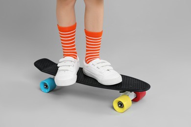 Little boy with skateboard on light grey background, closeup