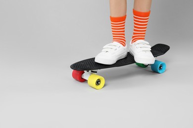 Photo of Little boy with skateboard on light grey background, closeup. Space for text