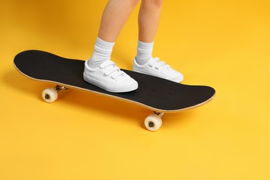 Photo of Little girl with skateboard on yellow background, closeup