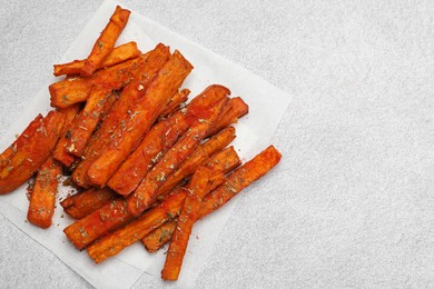 Photo of Delicious sweet potato fries with spices on light grey table, top view. Space for text