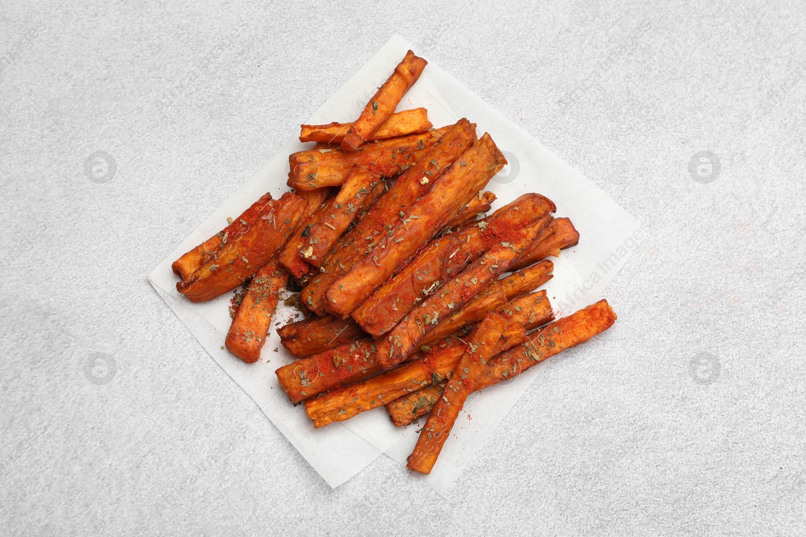 Photo of Delicious sweet potato fries with spices on light grey table, top view