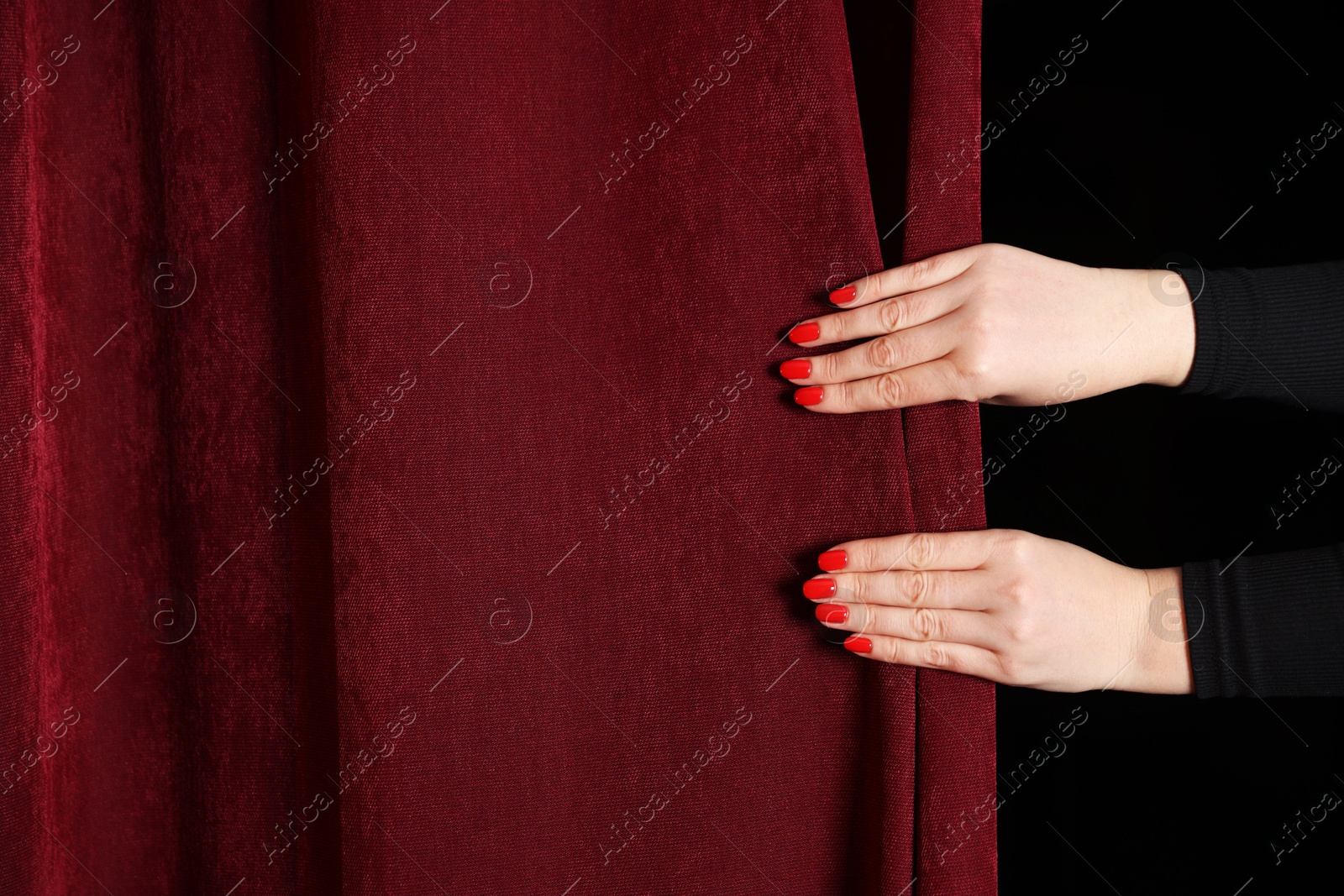 Photo of Woman closing red front curtains in theatre, closeup