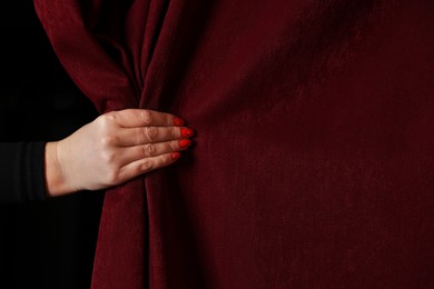 Photo of Woman closing red front curtains in theatre, closeup