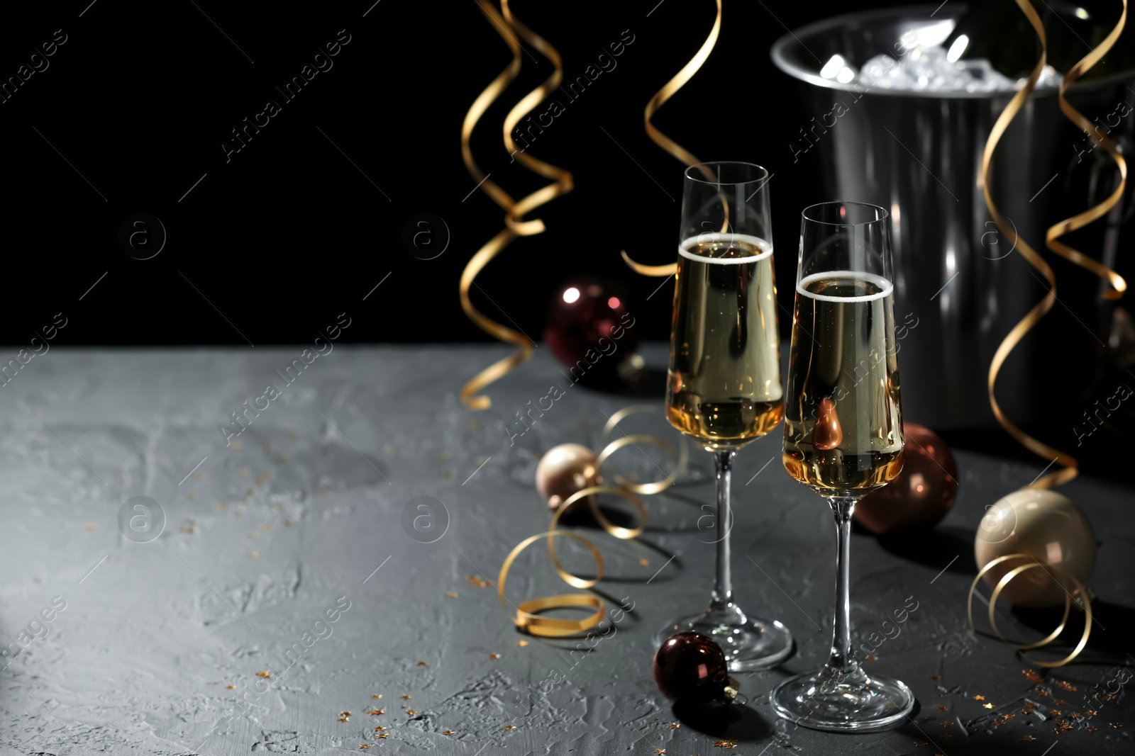 Photo of Champagne in glasses and Christmas decor on grey table, space for text