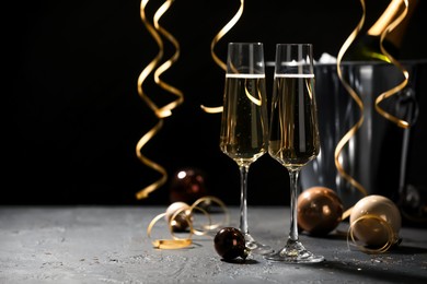 Photo of Champagne in glasses and Christmas decor on grey table, space for text