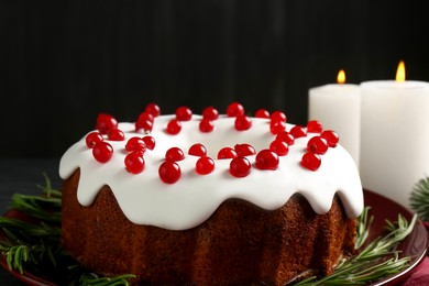 Photo of Tasty Christmas cake with red currants and rosemary on black table, closeup