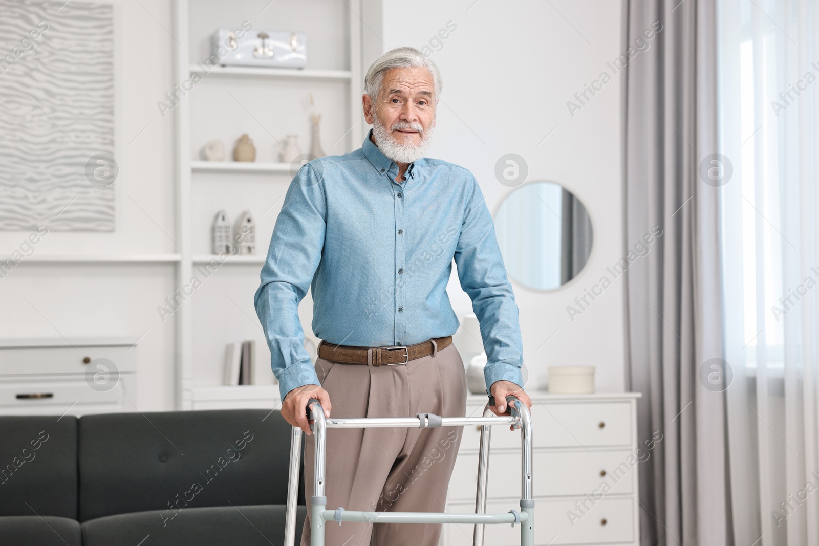 Photo of Senior man using walking frame at home