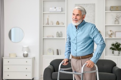 Photo of Senior man using walking frame at home. Space for text