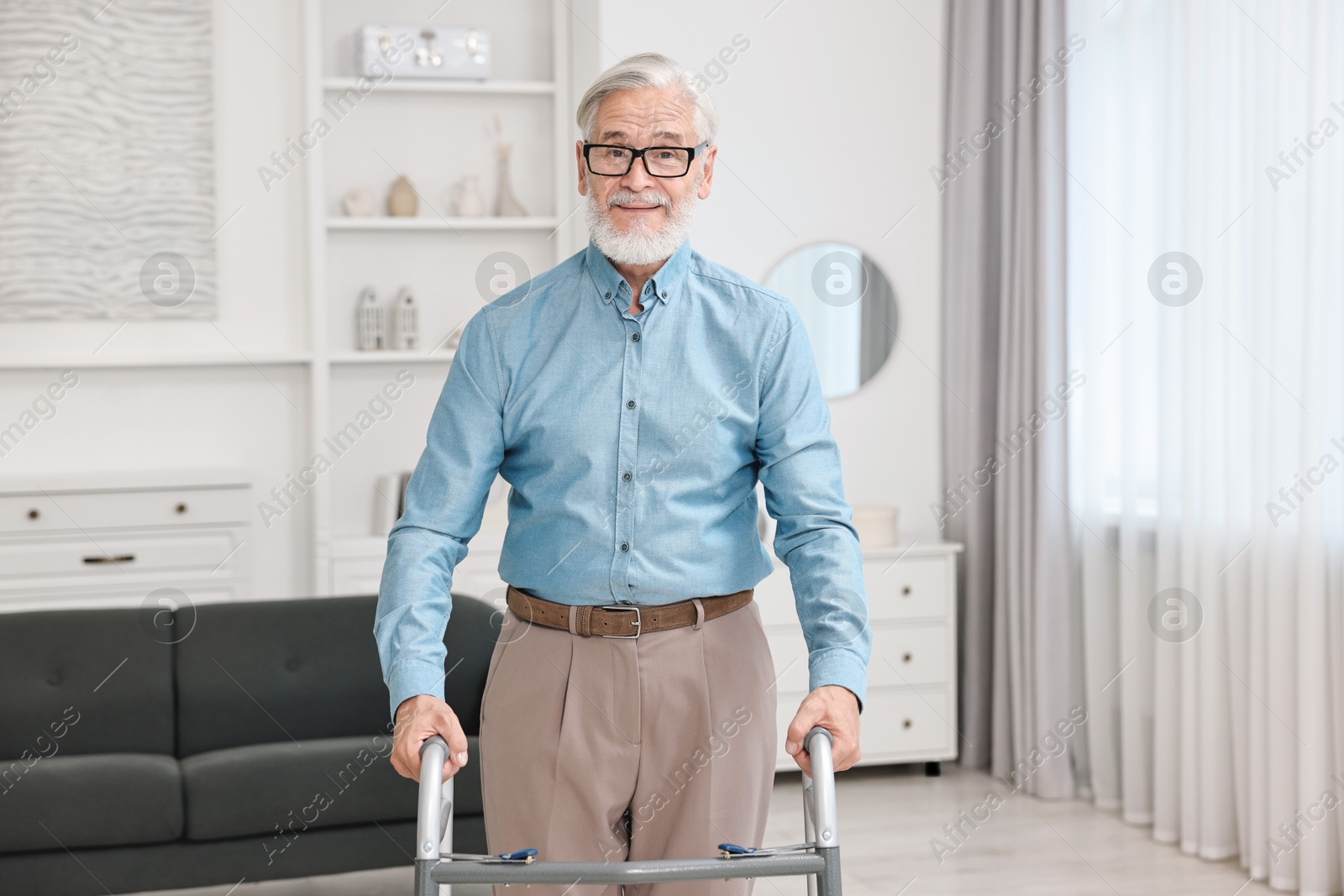 Photo of Senior man using walking frame at home