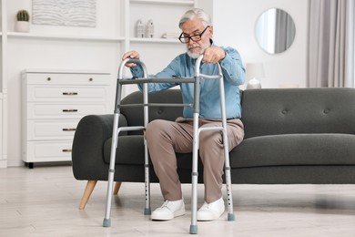 Photo of Senior man with walking frame on sofa at home