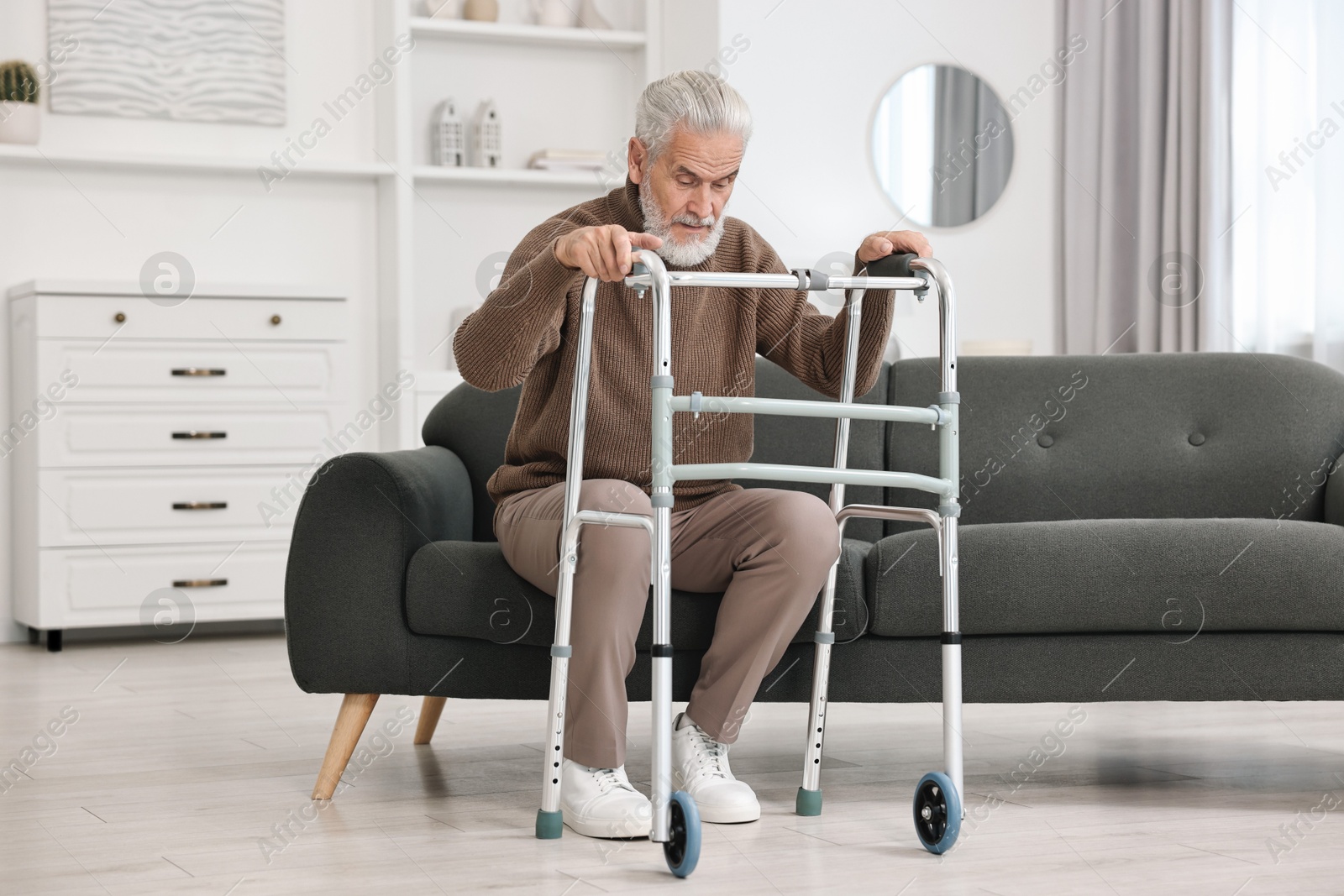 Photo of Senior man with walking frame on sofa at home