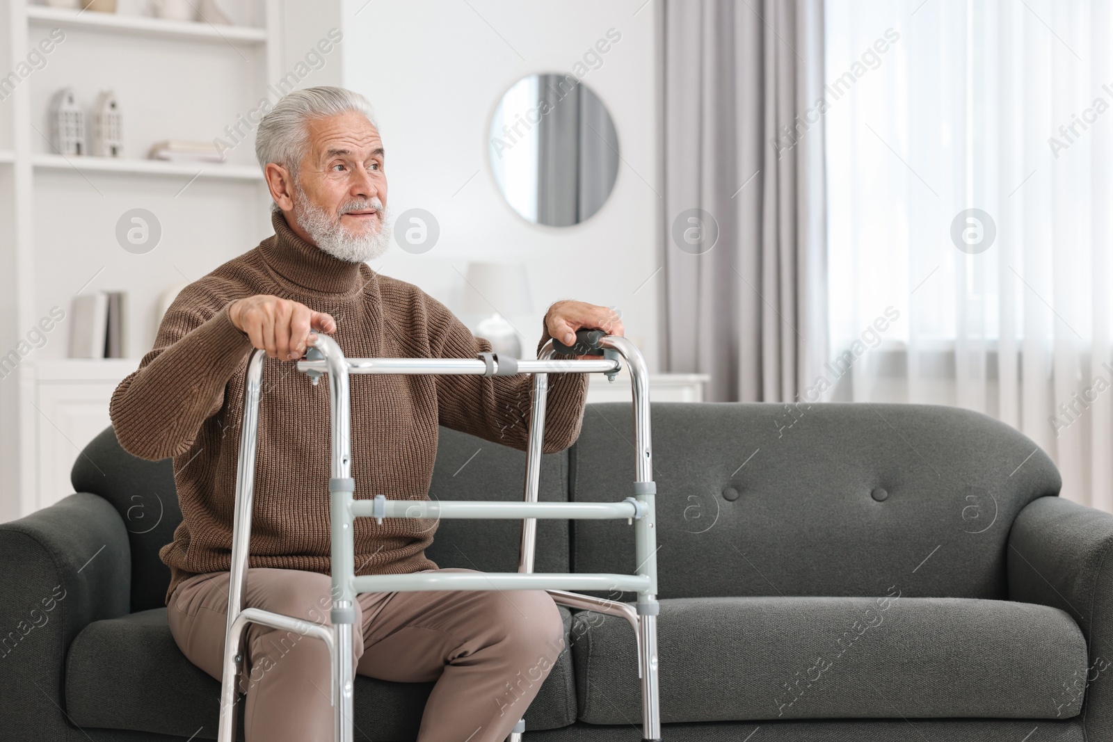 Photo of Senior man with walking frame on sofa at home