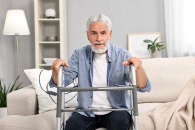 Photo of Senior man with walking frame on sofa at home