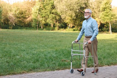 Photo of Senior man with walking frame in park, space for text