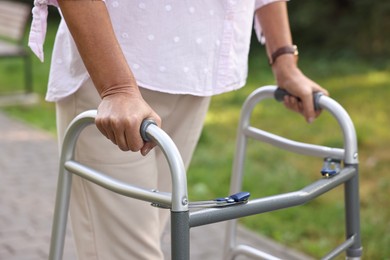 Photo of Senior woman with walking frame in park, closeup