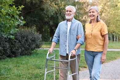 Photo of Senior couple with walking frame in park, space for text