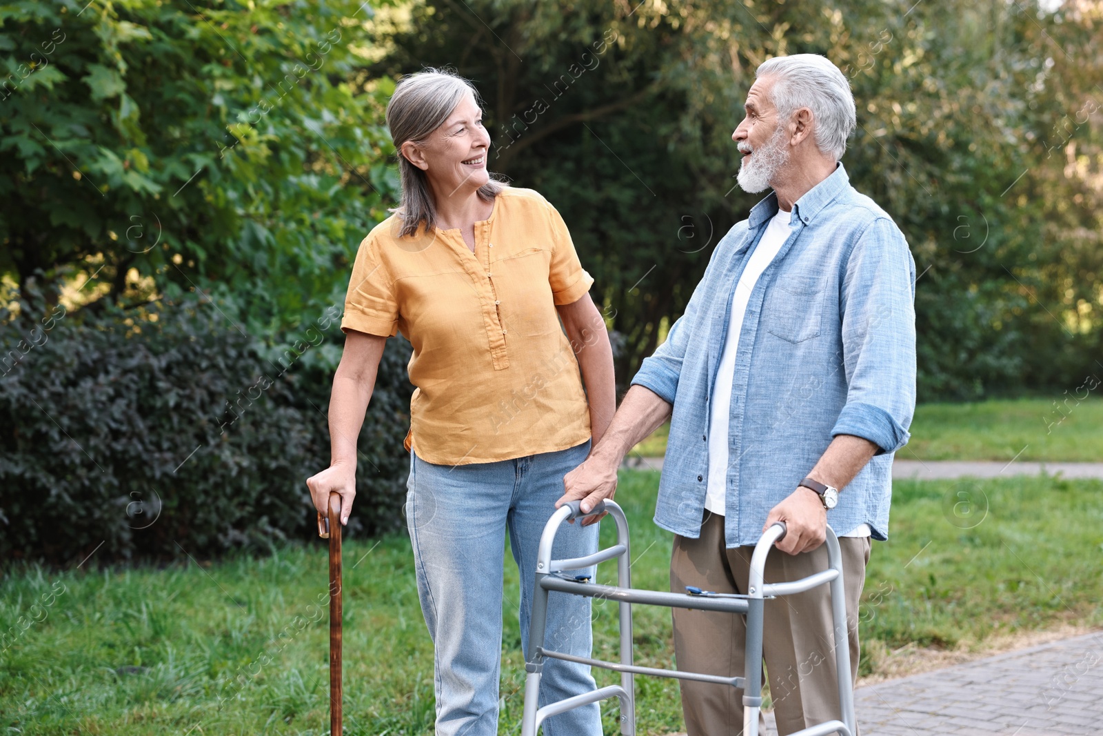 Photo of Senior couple with walking frame and cane in park