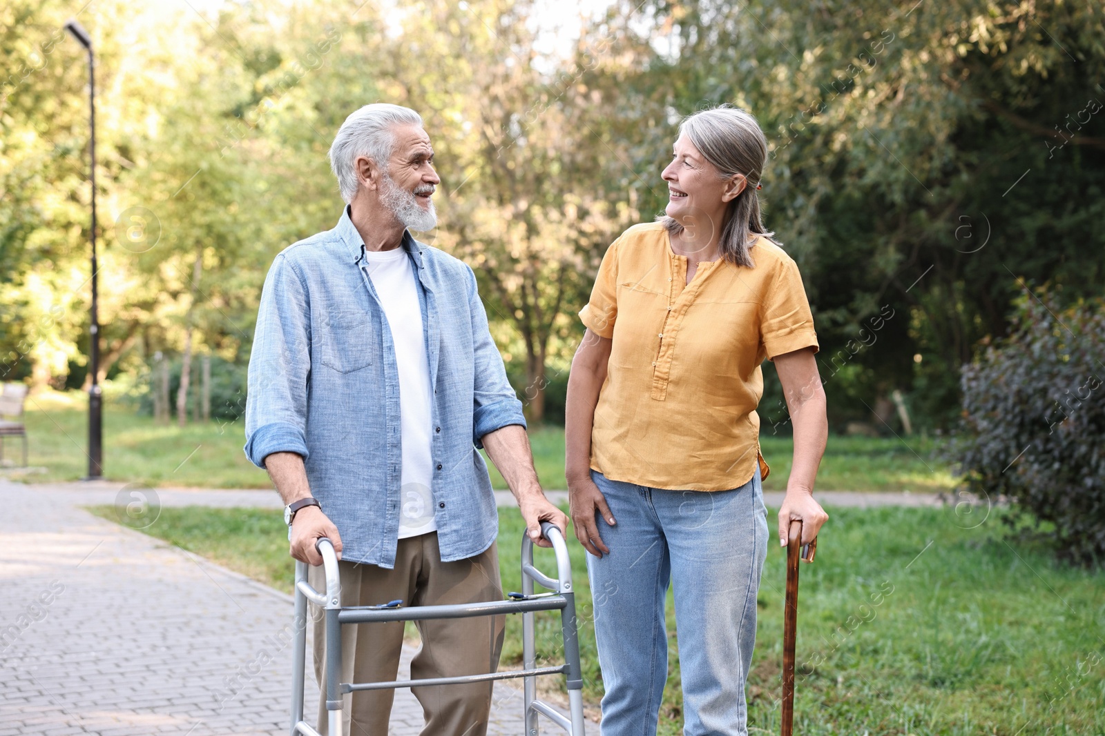 Photo of Senior couple with walking frame and cane in park