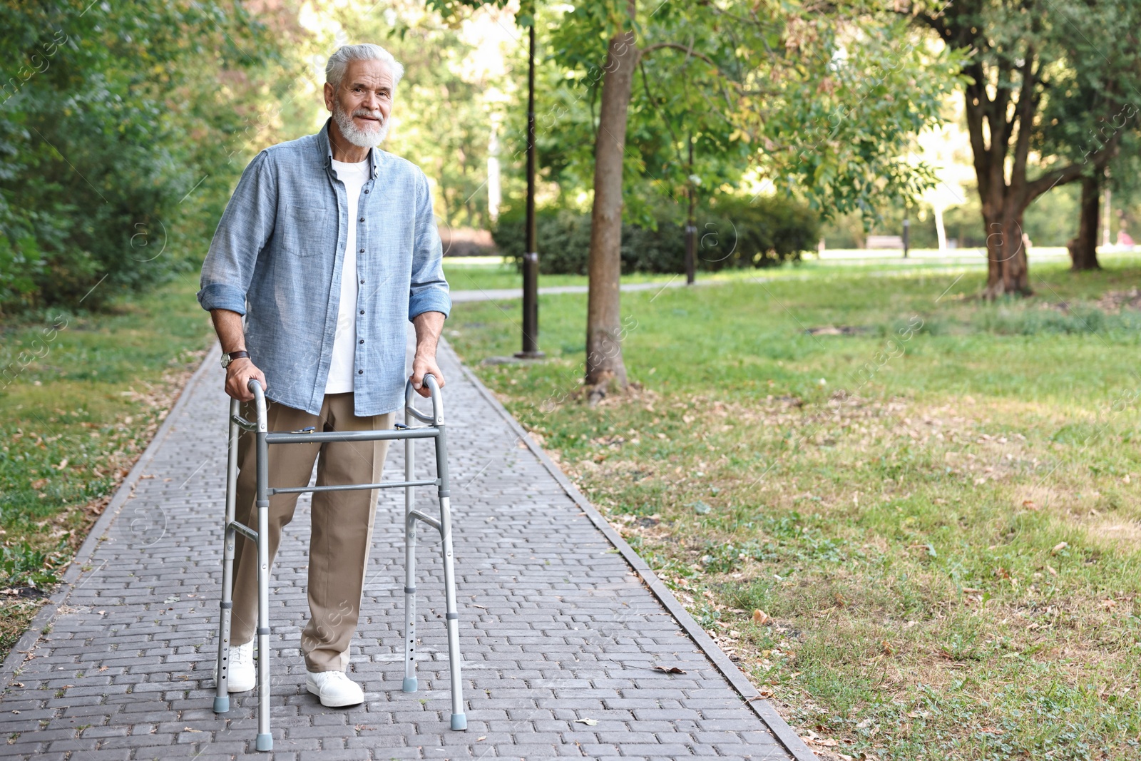 Photo of Senior man with walking frame in park, space for text