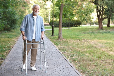 Photo of Senior man with walking frame in park, space for text