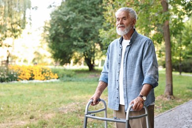 Photo of Senior man with walking frame in park, space for text