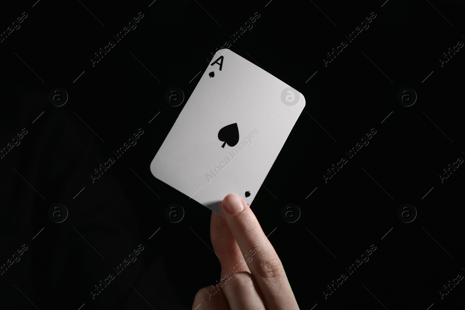 Photo of Woman with playing card against black background, closeup