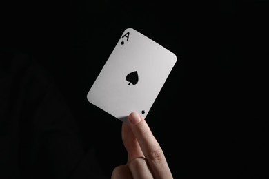 Woman with playing card against black background, closeup