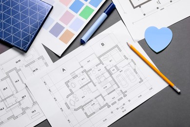 Designer's workplace with house plans, color palettes and stationery on grey table, flat lay