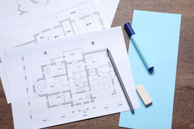 Photo of Designer's workplace with house plans and stationery on wooden table, flat lay