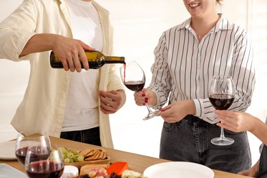 Photo of People with red wine and snacks indoors, closeup