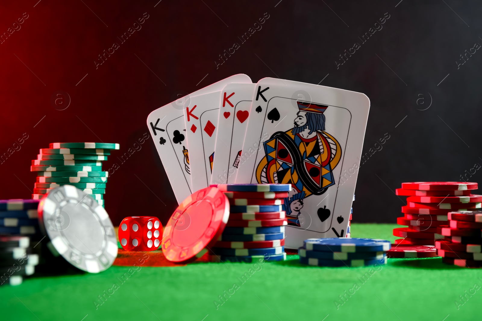 Photo of Poker chips, dice and playing cards on green table in neon lights, closeup