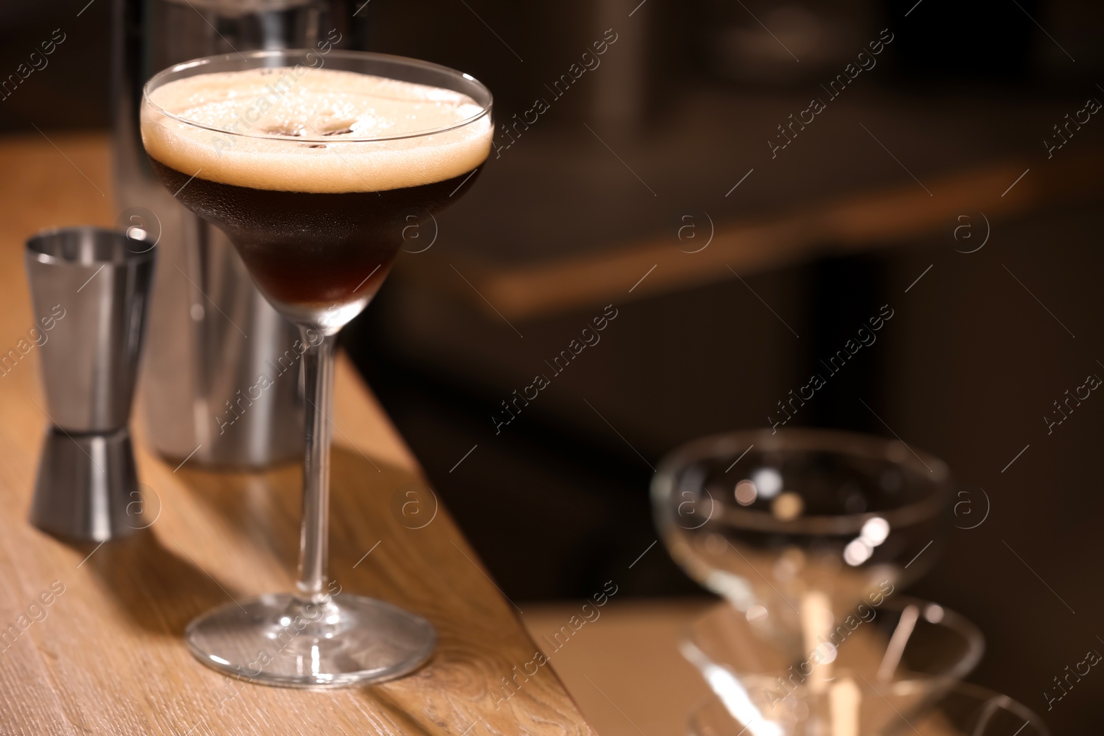 Photo of Glass with delicious espresso martini on wooden table in bar. Space for text