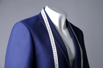 Photo of Male mannequin with blue jacket and measuring tape on grey background, closeup