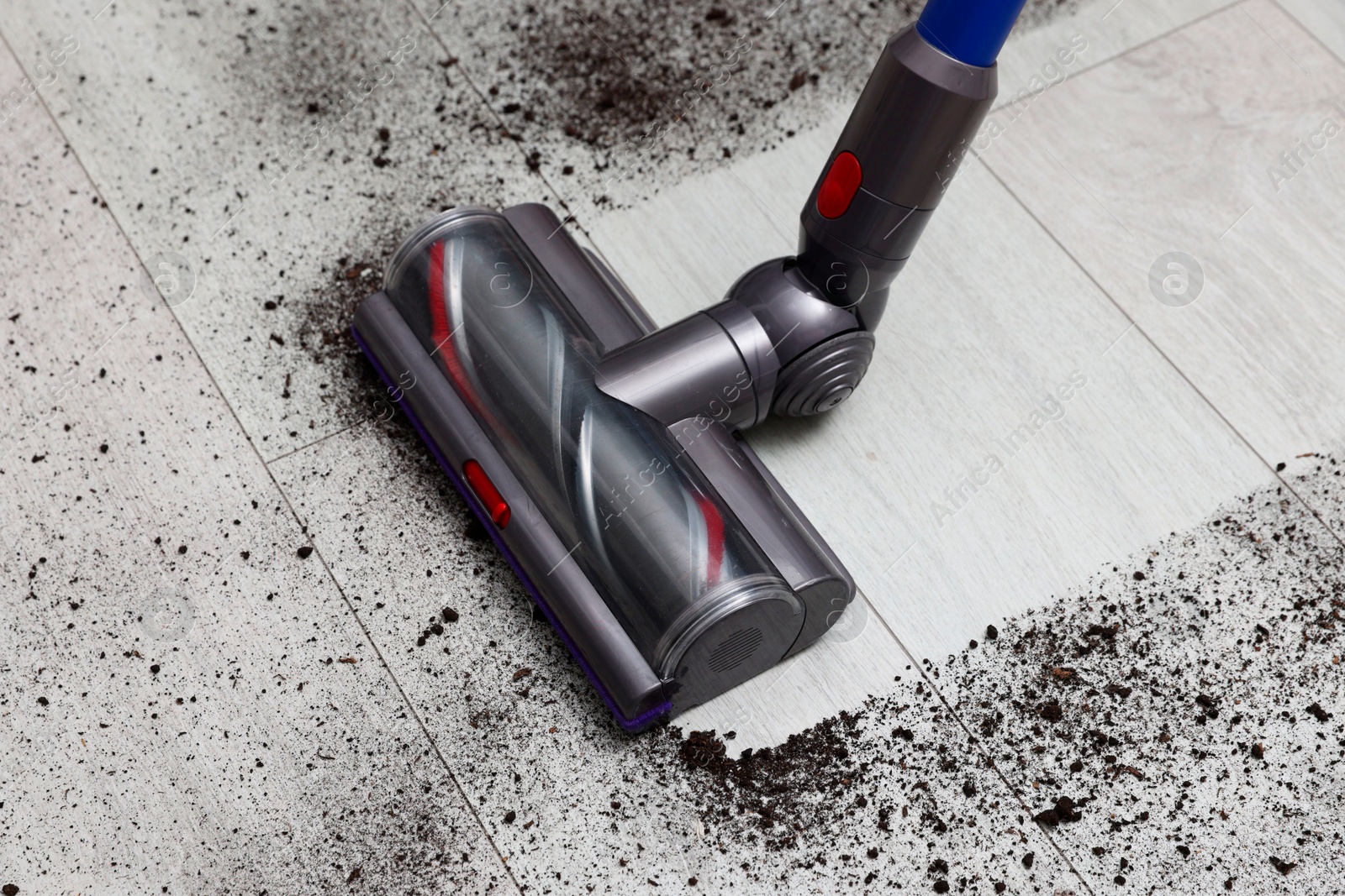 Photo of Cleaning floor with cordless vacuum cleaner indoors, closeup