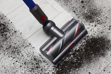 Photo of Cleaning floor with cordless vacuum cleaner indoors, above view