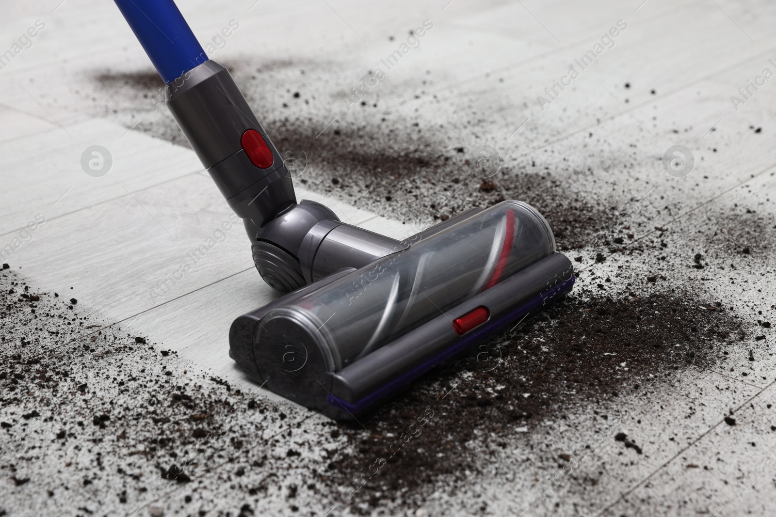 Photo of Cleaning floor with cordless vacuum cleaner indoors, closeup