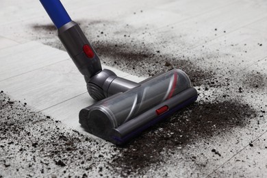 Photo of Cleaning floor with cordless vacuum cleaner indoors, closeup