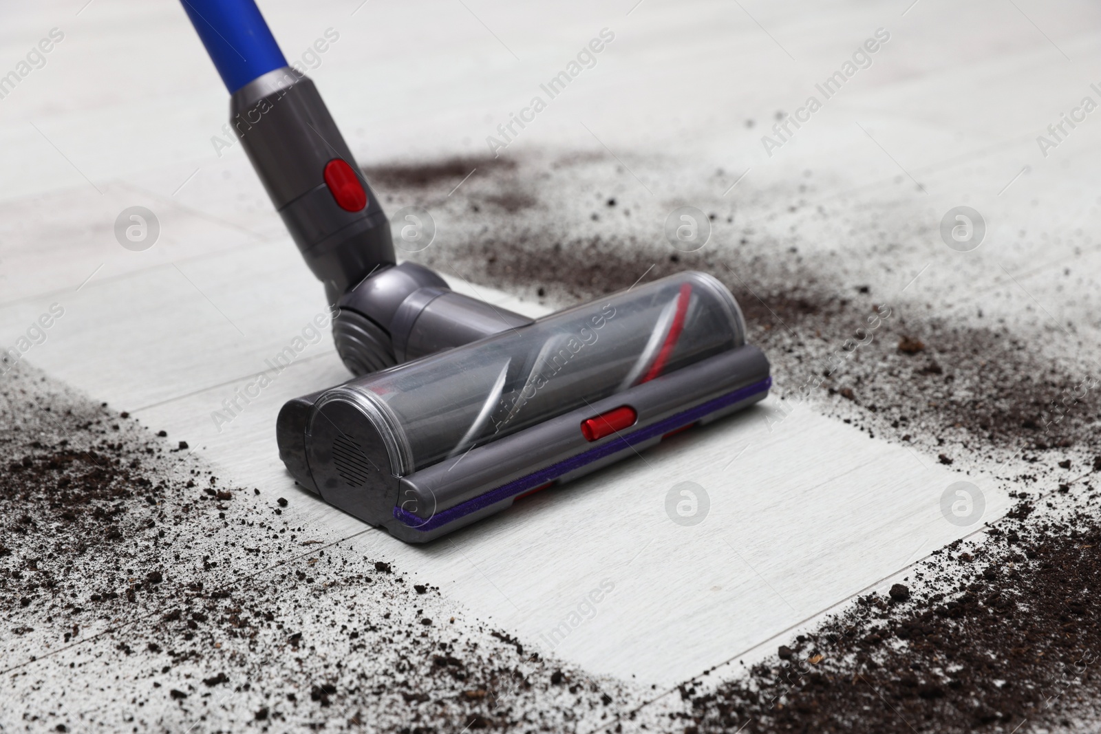 Photo of Cleaning floor with cordless vacuum cleaner indoors, closeup