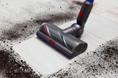 Photo of Cleaning floor with cordless vacuum cleaner indoors, closeup