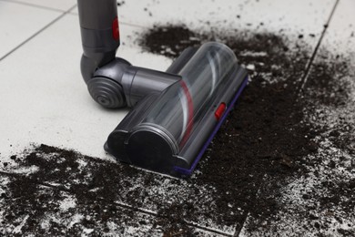 Photo of Cleaning floor with cordless vacuum cleaner indoors, closeup