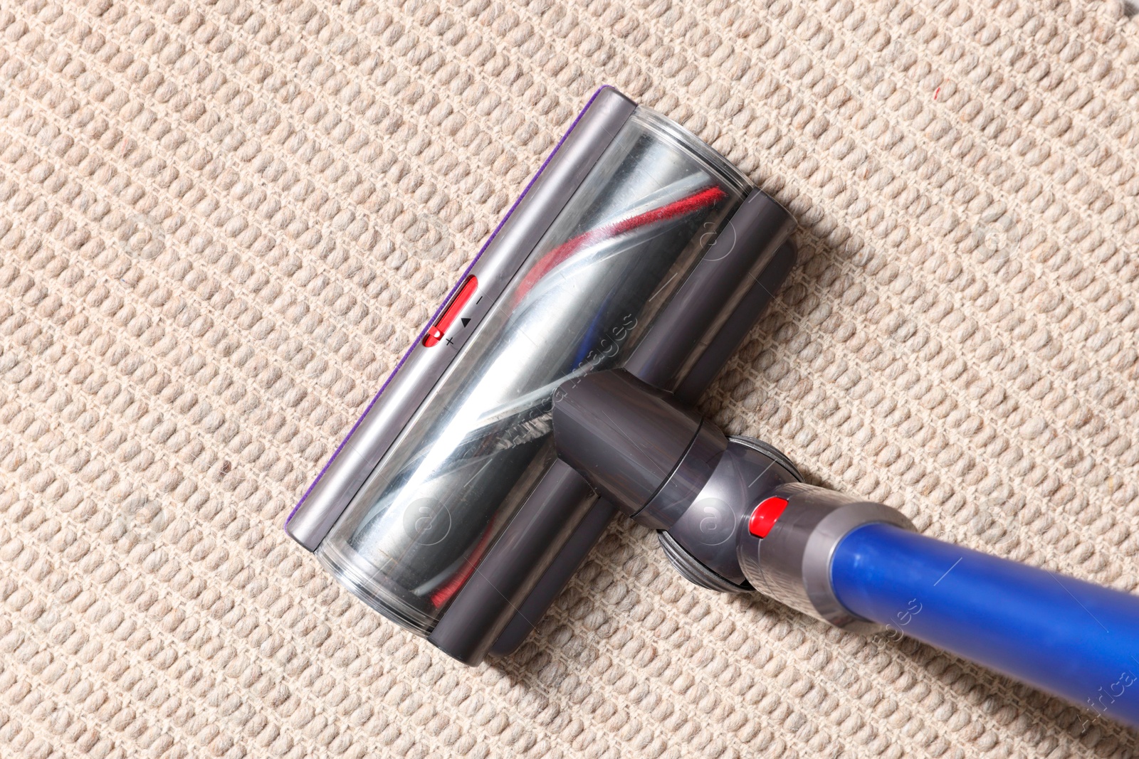 Photo of Cleaning carpet with cordless vacuum cleaner indoors, top view