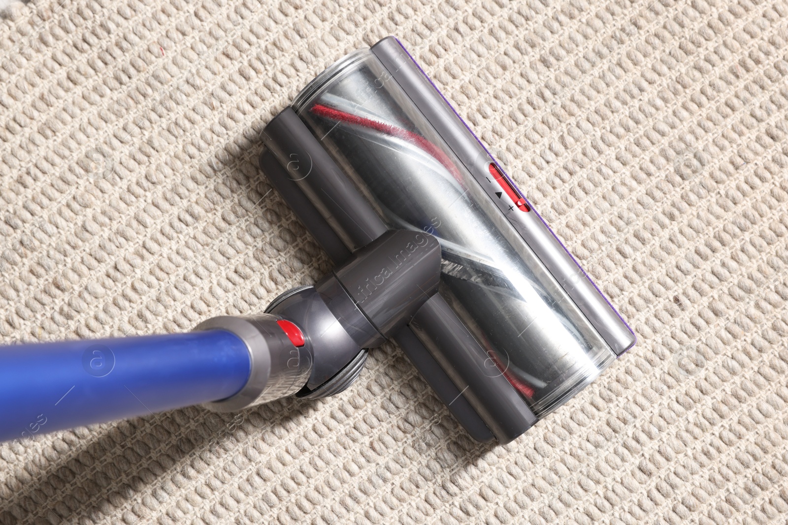 Photo of Cleaning carpet with cordless vacuum cleaner indoors, top view