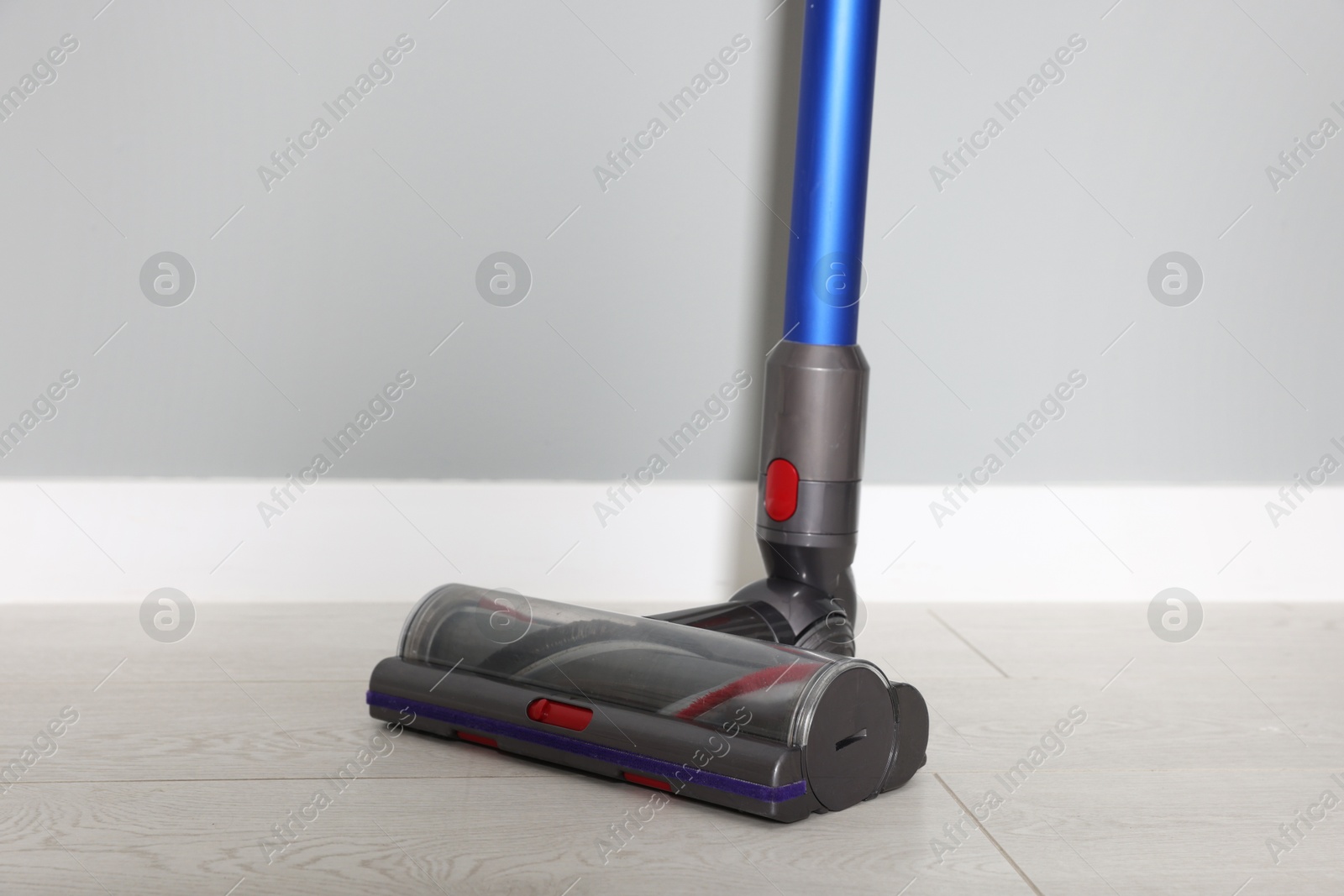 Photo of One cordless vacuum cleaner near grey wall indoors, closeup