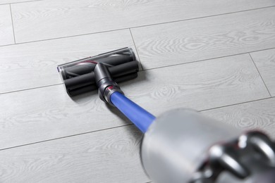 Photo of Cleaning floor with cordless vacuum cleaner indoors, closeup