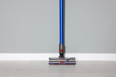 Photo of One cordless vacuum cleaner near grey wall indoors